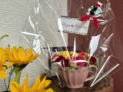 誕生日メッセージのついたカップに寄せ植えしたバラの花